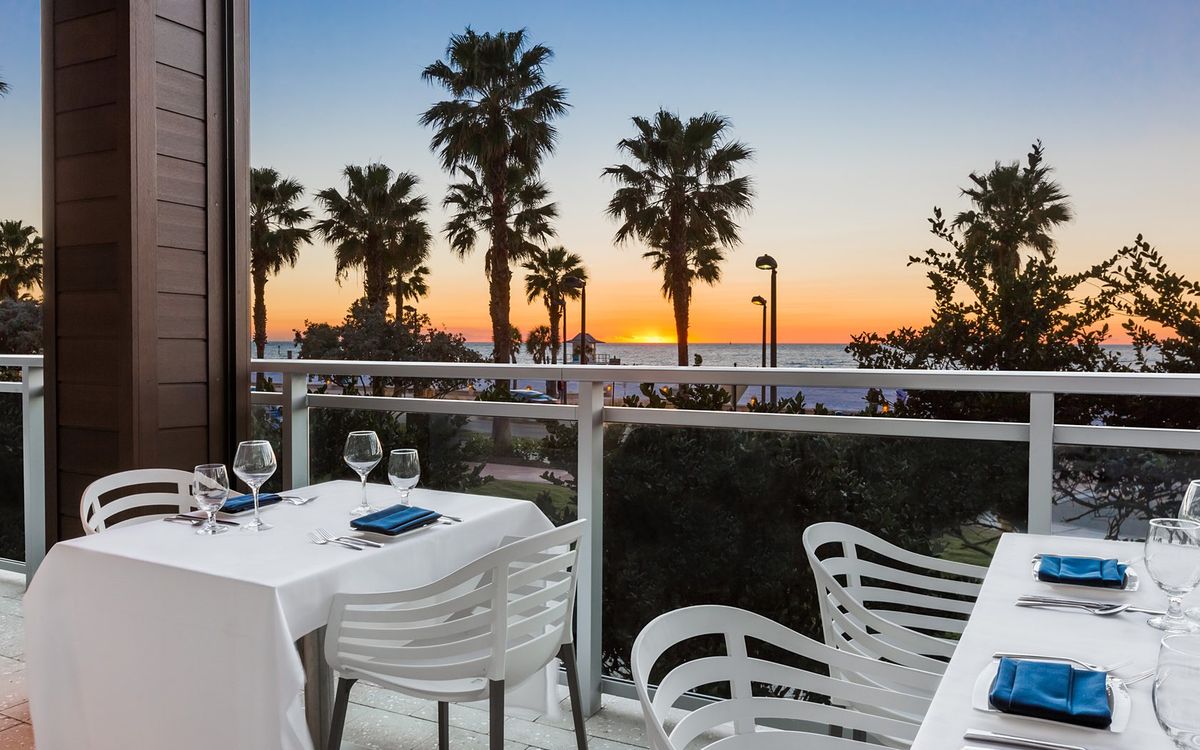 A terrace dining table at sunset, looking out over palm trees